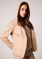Woman wearing a beige hoodie and pants against a plain background